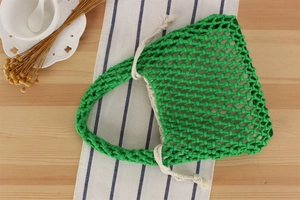Detail view of grass green macrame woven beach bag with secure white drawstring closure