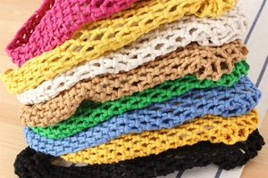 Macro detail of various colorful macaron-style hand-woven crochet beach bags stacked together