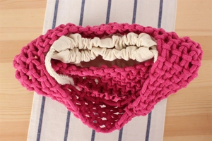 Detail of rose red woven bucket bag with cream canvas drawstring lining and thick cotton cord