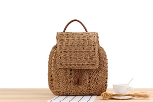 Close-up of woven straw backpack featuring a leather handle and drawstring closure detail