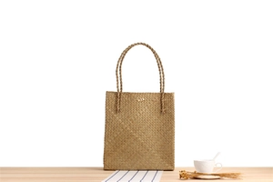 Detail of natural woven straw tote bag with wood button closure and rope handles