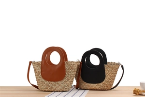 Close-up of woven straw handbag with circular leather handles and dual-tone finish