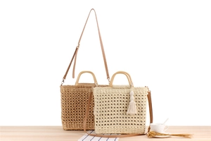 Detail of handmade straw woven bags in cream and tan with wood handles and tassels