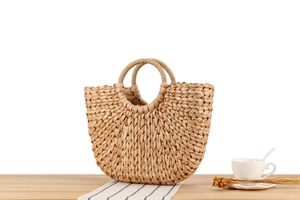 Close-up of handmade corn husk woven tote bag with smooth inner lining on a wooden table