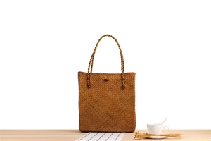 Detail of vintage woven straw shoulder bag with natural texture on a wooden table
