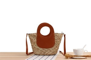 Detail of hand-woven straw tote with brown leather handles and a summer vacation vibe