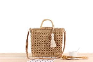 Detail of hollow-out woven paper rope bag with wooden handle and white cotton tassel