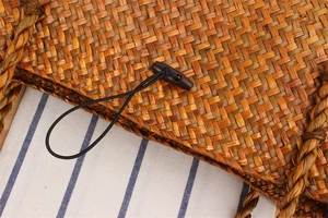 Close-up of handmade woven straw bag featuring a dark wooden button and textured details