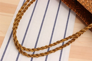 Detail of hand-woven straw shoulder bag with durable twisted rope handles and natural texture