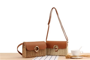 Close-up of woven straw crossbody bags with leather flap and gold metal ring detail