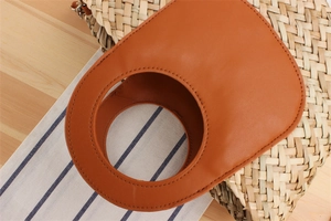 Detailed macro view of woven straw bag with leather handle and silver metal ring