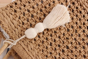 Close-up of paper rope woven beach bag with bamboo handle and white cotton tassels