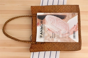 Close-up of handwoven straw tote bag with intricate texture on a light wood background