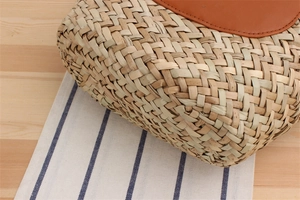 Close-up of the natural straw fiber woven texture and tan leather trim on the tote bag