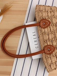 Handmade woven straw tote bag with brown leather handles and plaid lining texture