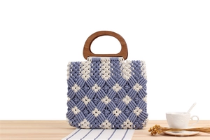 Detail of blue and white macrame woven tote bag with smooth round wooden handles