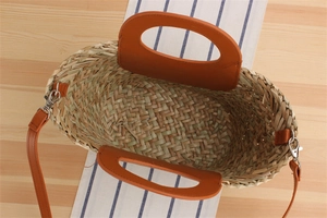 Top view of woven straw tote bag with brown leather straps on striped fabric