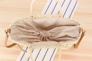 Macro view of woven straw bag interior with fabric lining and drawstrings on wood