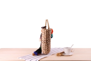 Detail of handmade corn husk bag with colorful pompoms and tassels on striped cloth