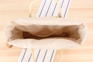 Internal view of a woven straw tote bag featuring beige fabric lining and a small side pocket