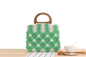Detail of green plaid woven cotton bag featuring natural wood handles on a wooden table