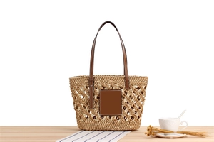 Close-up of hollow woven pattern on beige paper straw tote with brown leather strap