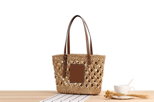 Detail of handmade woven beach bag featuring contrast paper rope and brown leather patch