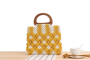 Detail of macramé hand-woven tote bag with yellow geometric pattern and D-shaped wooden handle