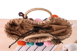 Top view of large woven corn husk bag with colorful pom-poms and drawstring lining