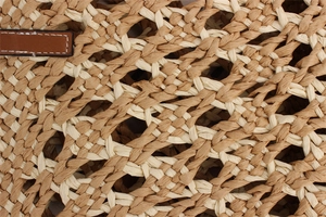 Macro detail of two-tone woven paper rope beach bag with honeycomb texture and leather strap