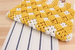 Detailed close-up of yellow and white checkered cotton rope weaving on a wood table