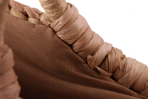 Close-up of woven corn husk bag detail showing brown fabric lining and handcrafted handle