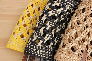 Detail of woven beach bag showing colorful diamond patterns and leather handles