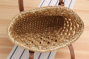 Top view of handmade woven beach bag with contrasting colors and brown leather handles