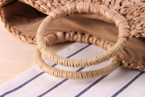 Close-up detail of hand-woven corn husk bag featuring a round handle and fabric lining