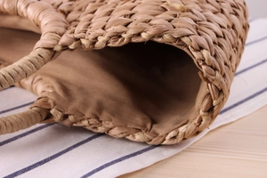 Close-up of woven corn husk handbag showing dense texture and soft fabric lining