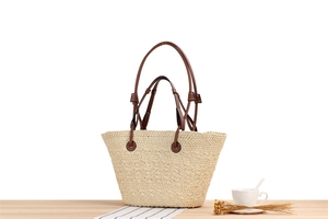 Detail of hand-woven paper rope beach tote bag with dual brown leather handles