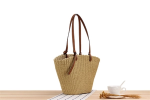 Close-up of beige woven paper rope tote bag with wavy edges and brown leather handles