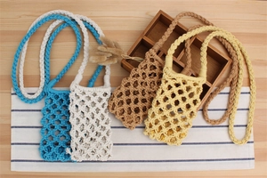 Flat lay of colorful woven cotton rope phone bags on a wooden tray in boho style