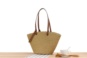 Detail of large woven paper rope tote bag featuring brown leather handles and scalloped edges