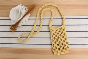 Close-up of handmade yellow woven cotton phone bag with hollow diamond mesh pattern