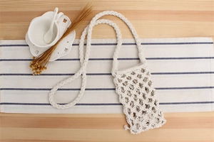 Detailed macro view of cream woven cotton macrame phone bag with braided strap
