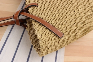 Close-up of beige woven paper rope bag with brown leather strap detail and knot