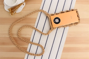 Detailed view of handmade woven cotton crossbody phone bag with orange smartphone inside