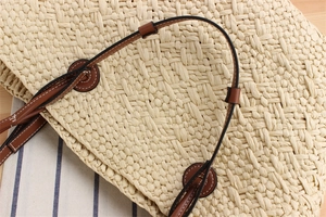 Close-up of beige woven paper rope tote with brown leather strap and stitch detail