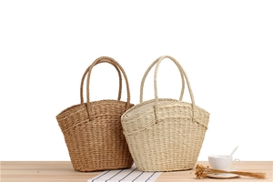 Detail showing handwoven paper rope tote bags in brown and beige on a wooden table