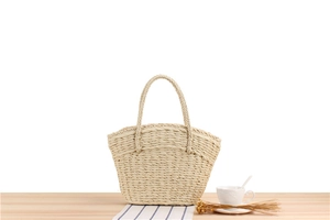 Artistic layout of a handwoven paper straw tote bag with dried flowers and coffee
