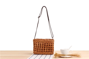Detail of hand-woven hollow pattern on brown straw crossbody bag with leather strap