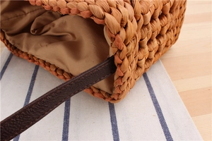 Detail of woven straw shoulder bag featuring high-quality fabric lining and leather strap