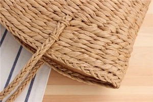 Close-up of the woven paper rope texture and reinforced edge of the straw handbag